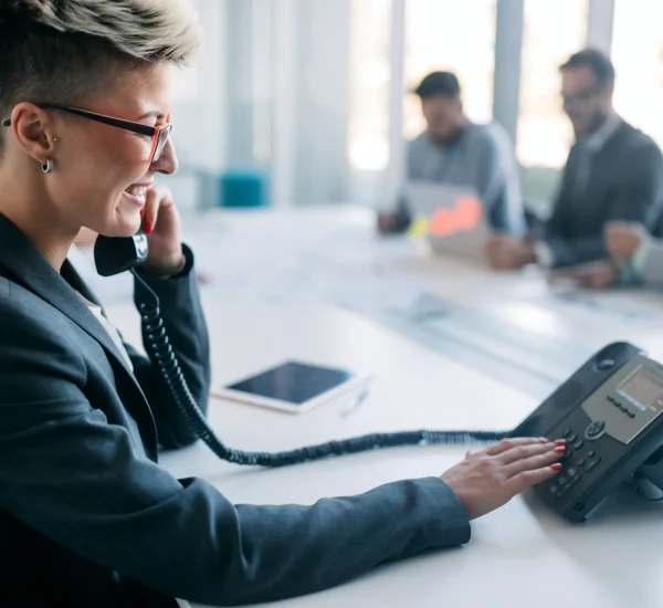 Modern office with executives using enterprise IP phones connected to a cloud communication platform.